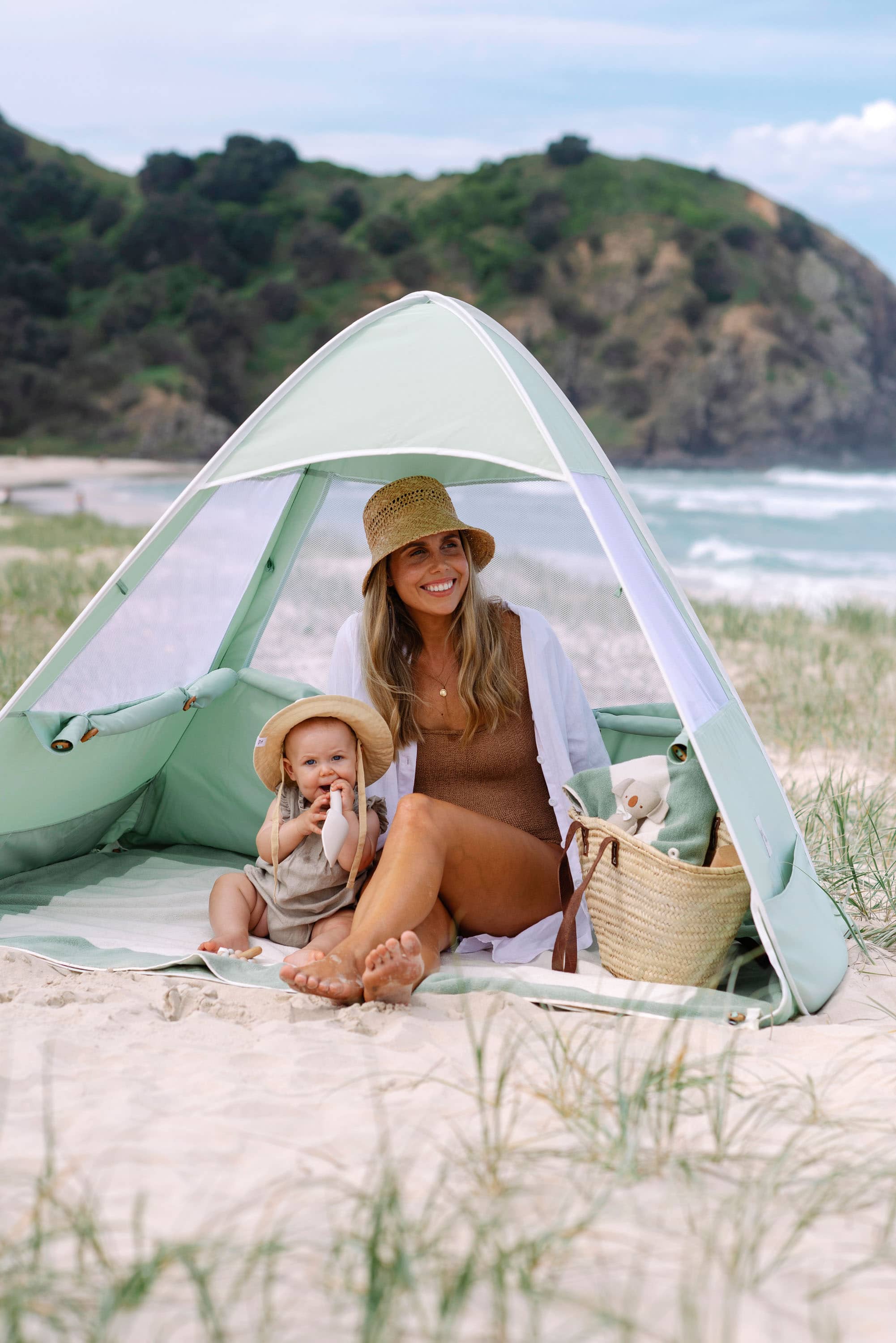 Picture of a woman and her baby enjoying time together on the beach under a sunshade