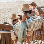 Family carying a striped chair at the beach with ocean view