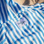 Close-up of a blue and white striped beach poncho with a lozi and gabe label on the back