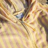 Close-up of a yellow and pink striped beach poncho with a lozi and gabe tag.
