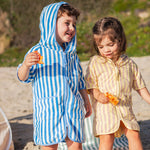 Two children on a beach wearing hooded cover-ups.