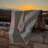 Striped towel draped over a railing with a sunset and mountains in the background